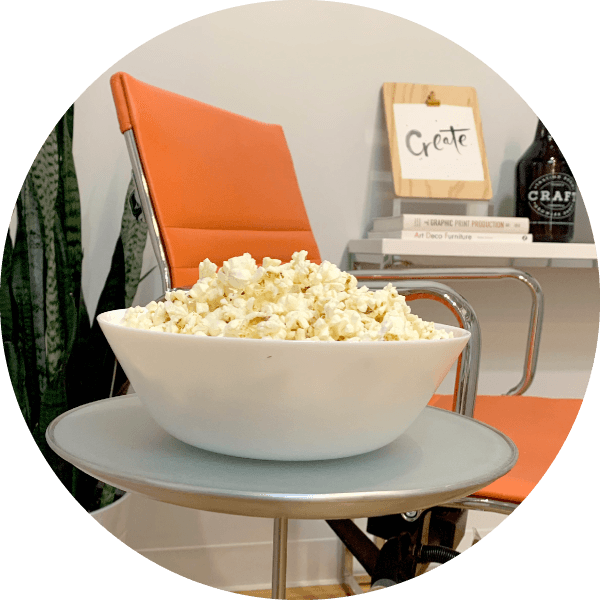 Bowl of popcorn on table by chair