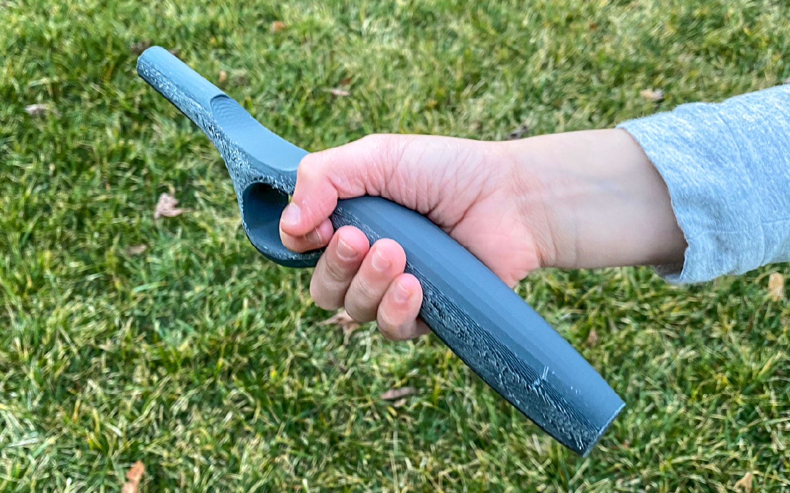 child's hand holding a 3d print of a fishing rod concept