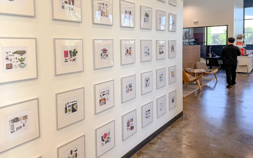 a wall of framed photos with a man walking away in the background
