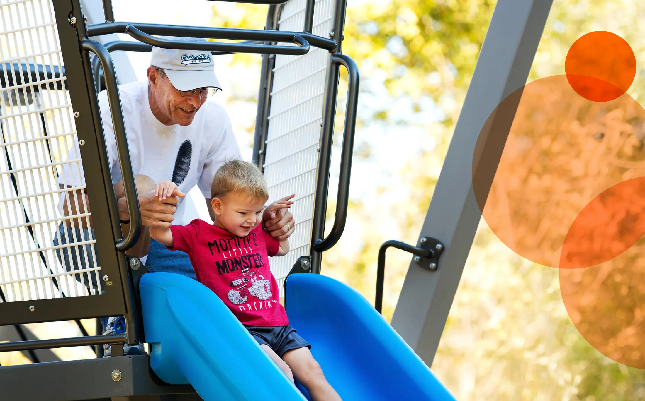 child on a slide at a park with an adult
